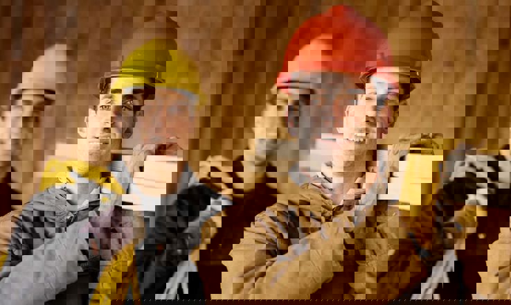 Two young carpenters carrying lumber