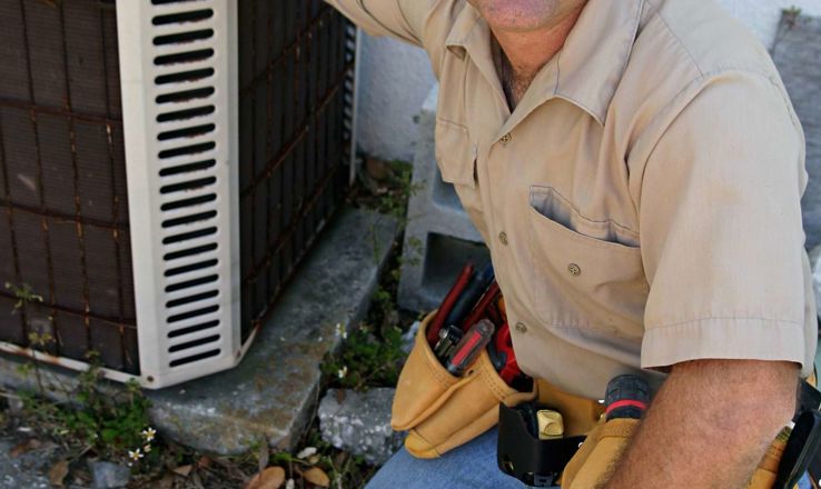 Man kneeling next to an AC unit